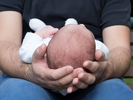 Father holding head of his newborn son in hands. Loving father hand holding cute sleeping newborn...