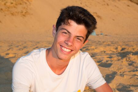 Handsome young man on the beach smiling at the cameraの写真素材