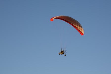 Motorised paraglider flying over mountains in summer dayの写真素材