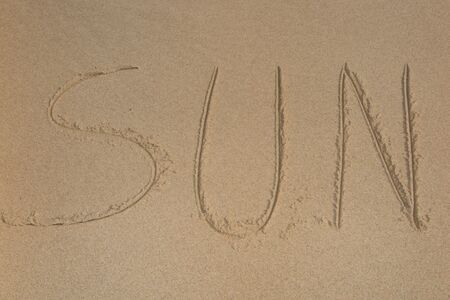 written word "Sun" on sand of beachの写真素材