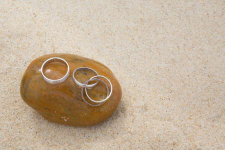 silver wedding rings on the sand on a sea beachの写真素材