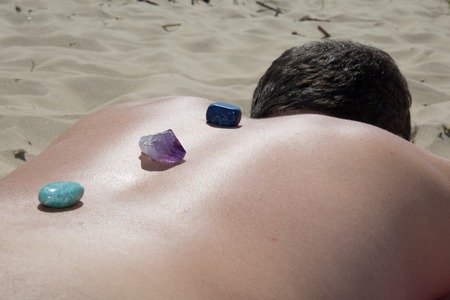 Crystal therapy, man's back on the beach having stoneの写真素材