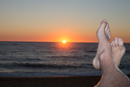 People feet on orange sea background, sunset landscapeの写真素材