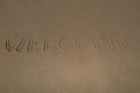 Text "welcome" on the beach sand summertimeの写真素材