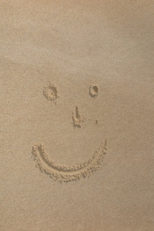 Smile face written in the sand on the beachの写真素材