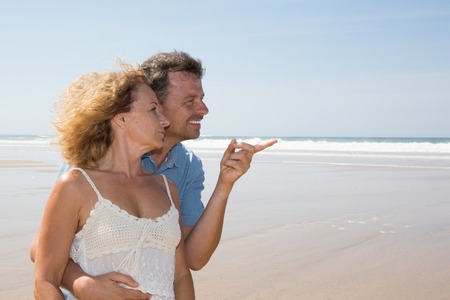Cheerful mature couple embracing by the beach