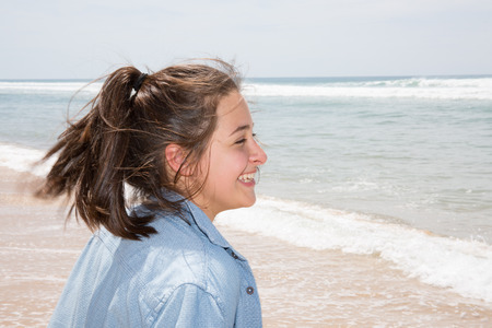 happy cheerful brunette teen girl on sand beachの写真素材