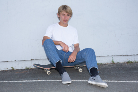 Skater in jeans riding on road against city backgroundの写真素材