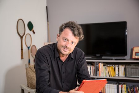 Cheerful young man in sofa with digital tabletの写真素材