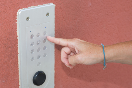 Close-up of person using building intercom