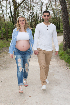 Pregnant woman with husband walking on meadowの写真素材