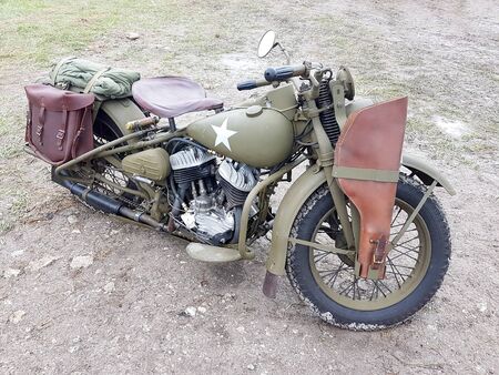 military motorcycle with a leather rifle holster attached to a front wheel. The vehicle is painted khaki or war color.の写真素材