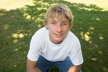 portrait of young blonde man sit on grassの写真素材