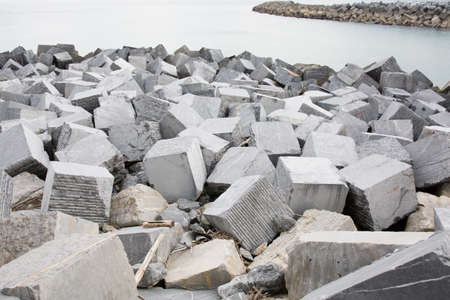 big grey stones against beach erosion in sea waterの写真素材