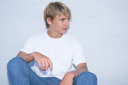 A young blond boy sitting on the floor in the streetの写真素材