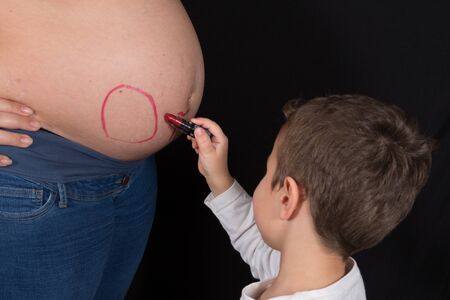 the first son makes a drawing on his mother mum pregnant bellyの写真素材