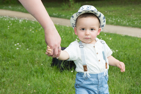 adorable boy portrait with mother hand in park