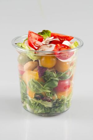 Salad with dressing in plastic container isolated on white backgroundの写真素材