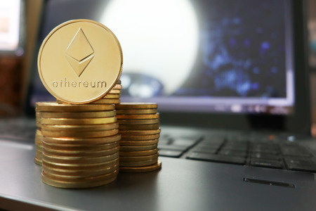 Stack of ether coins or ethereum on computer keyboard background to illustrate blockchain and cyber...