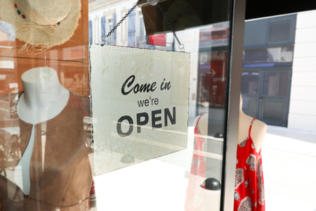 Business opening with open entrance sign in street shop through the glass of windowの写真素材
