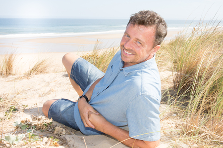 holydays handsome man lying on sand near beach vacation dunesの写真素材