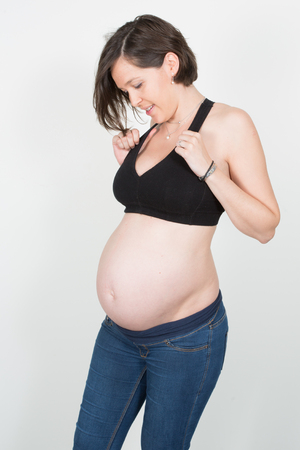 Portrait of a happy and proud pregnant woman looking at her belly in 7th monthの写真素材