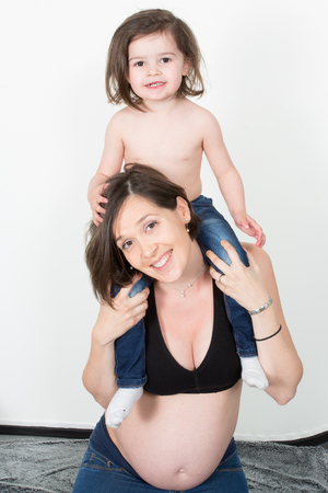 Beautiful pregnant woman play with her daughter at homeの写真素材