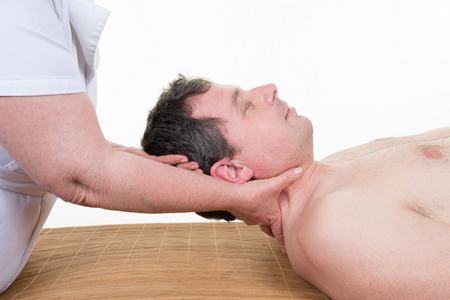 woman masseur doing neck massage on man in spa salonの写真素材