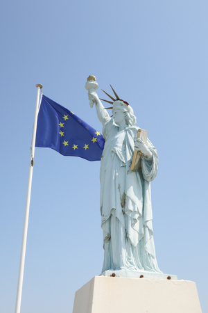 usa statue of liberty with the flag of europe in the wind concept of economiqyue and military allianceの写真素材