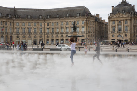 Bordeaux, Aquitaine / France - 06 10 2018 : girl dancing and splashing the water mirror in place de la bourse at Bordeaux, Franceのeditorial素材