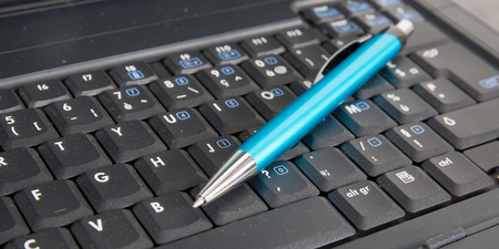 top view of a blue ballpoint pen resting on a laptop keyboardの写真素材