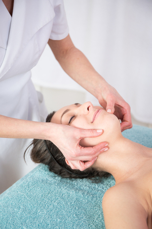 Face lifting and body face massage to beautiful girl in cosmetology cabinet or beauty spa parlorの写真素材