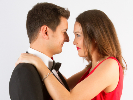 Elegant couple hug and kiss for the camera while holding each otherの写真素材