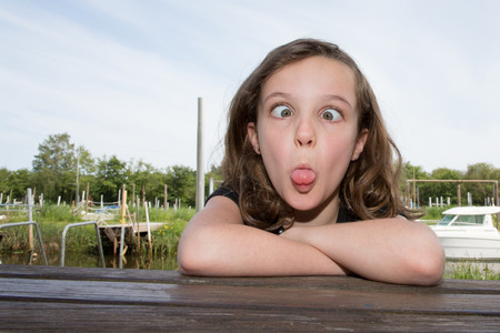 young girl makes faces in the head of fish to laugh outdoors