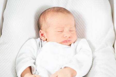 newborn baby sleeping on a white blanketの写真素材
