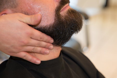 Man barber shaves his beard at the barber shopの写真素材