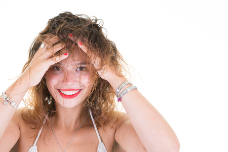portrait of one young cute woman hands on head hair on white backgroundの写真素材