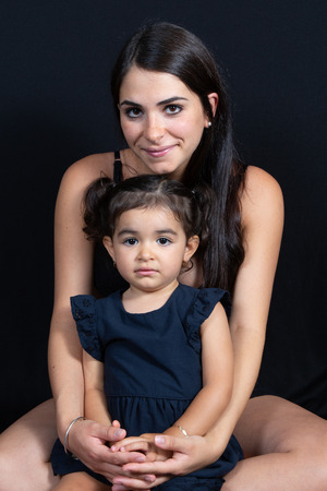child daughter sit on black floor with love pretty woman motherの写真素材