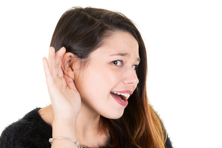 Beautiful woman puts hand to ear to hear better Young girl listening something over white background