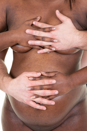 Man european american with affection and tenderness touching pregnant black african wife in love and tendernessの写真素材