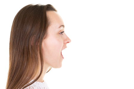 Profile of an angry young woman shouting in white backgroundの写真素材