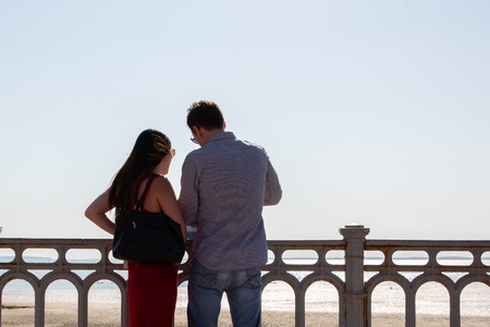 Back view of romantic tourist couple at city beach