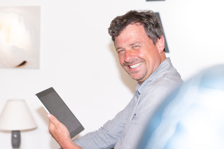 handsome man using tablet smiling at homeの写真素材