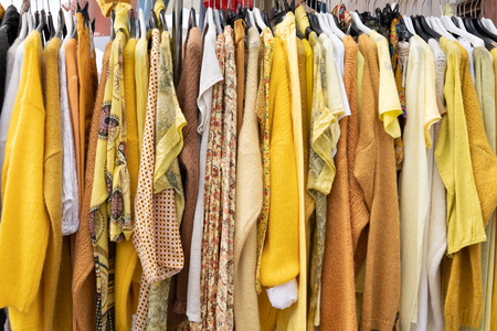 yellow woman clothes on hangers in store for backgroundの写真素材