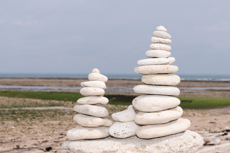 Pyramid of white grey stones on the sandy beach at ocean backgroundの写真素材
