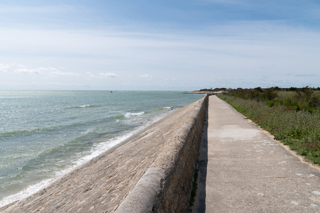 Coast and breakwater wave protection dike on Ile de RÃ© in France with the pathの写真素材