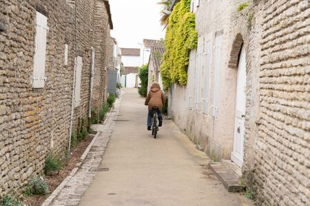 senior woman on bike in alleys on the Ile de Re in Franceの写真素材