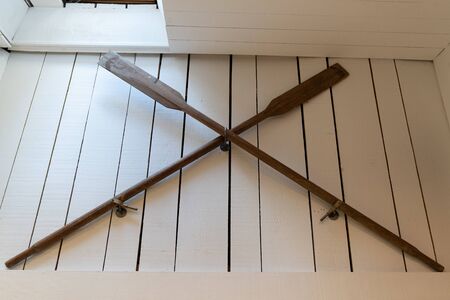 Old wooden boat oars paddle on white wall decoration