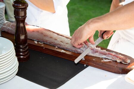 man chef cuts the salmon on the table