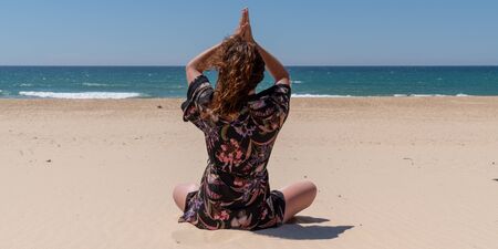behind of yoga woman meditates at the beach
